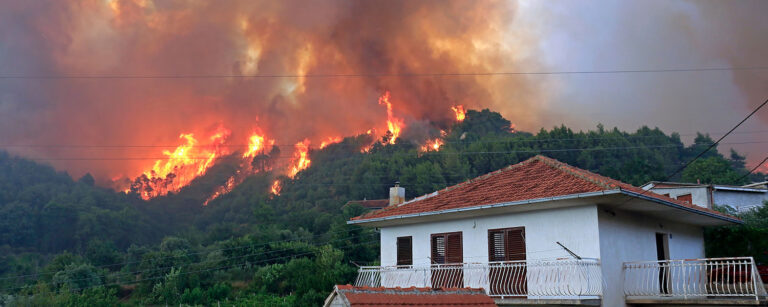 wildfire burning behind house