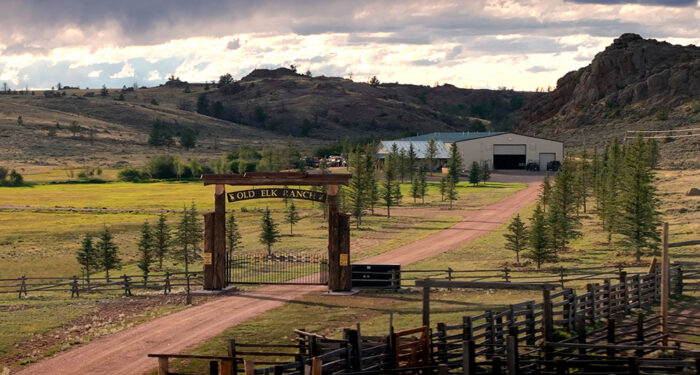 headquarters entrance with small mountain hills in the background and shop and home at end of driveway