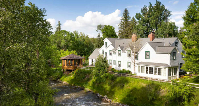 large white refurbished old farmhouse established along bank of creek