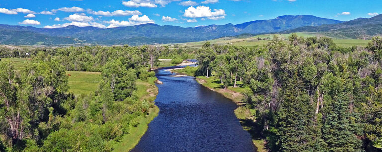 river flowing from the mountains through the tree-lined valley floor