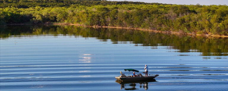 fishing off a boat in a pond surrounded by shrubs