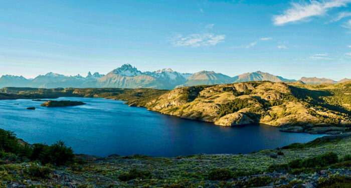 large dark blue lake in Chile with rugged hills and large mountain peaks
