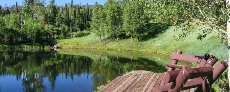 wood benches overlook small dock on mountain lake