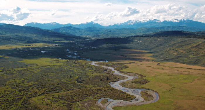 creek running through the middle of a brown meadow with distant mountains and nearby hills of wyoming ranch for sale