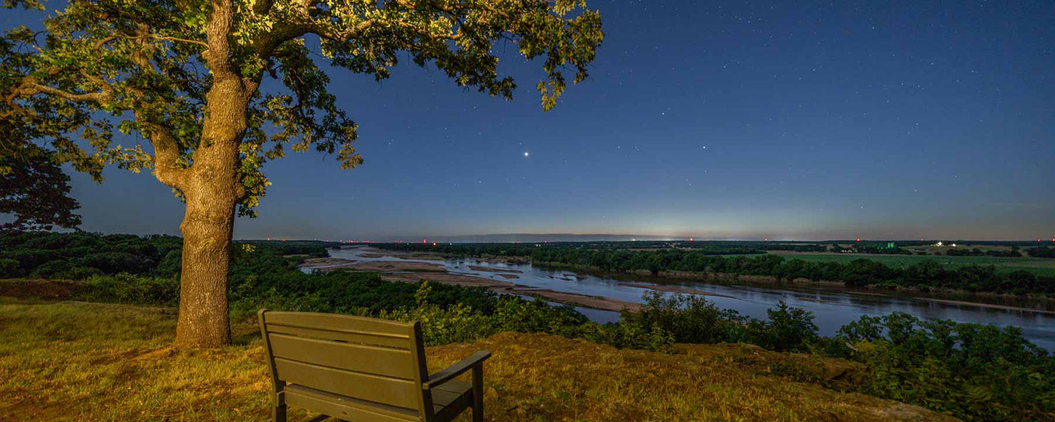 scenic overlook with bench at night with views of the Arkansas River with night sky filled with stars and setting sun