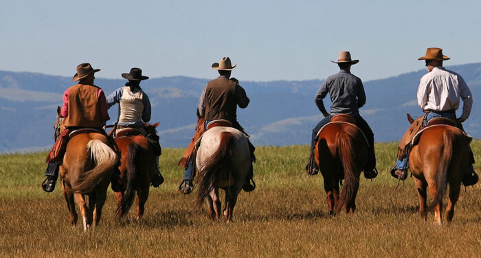 group of cowboys riding horseback into the distance
