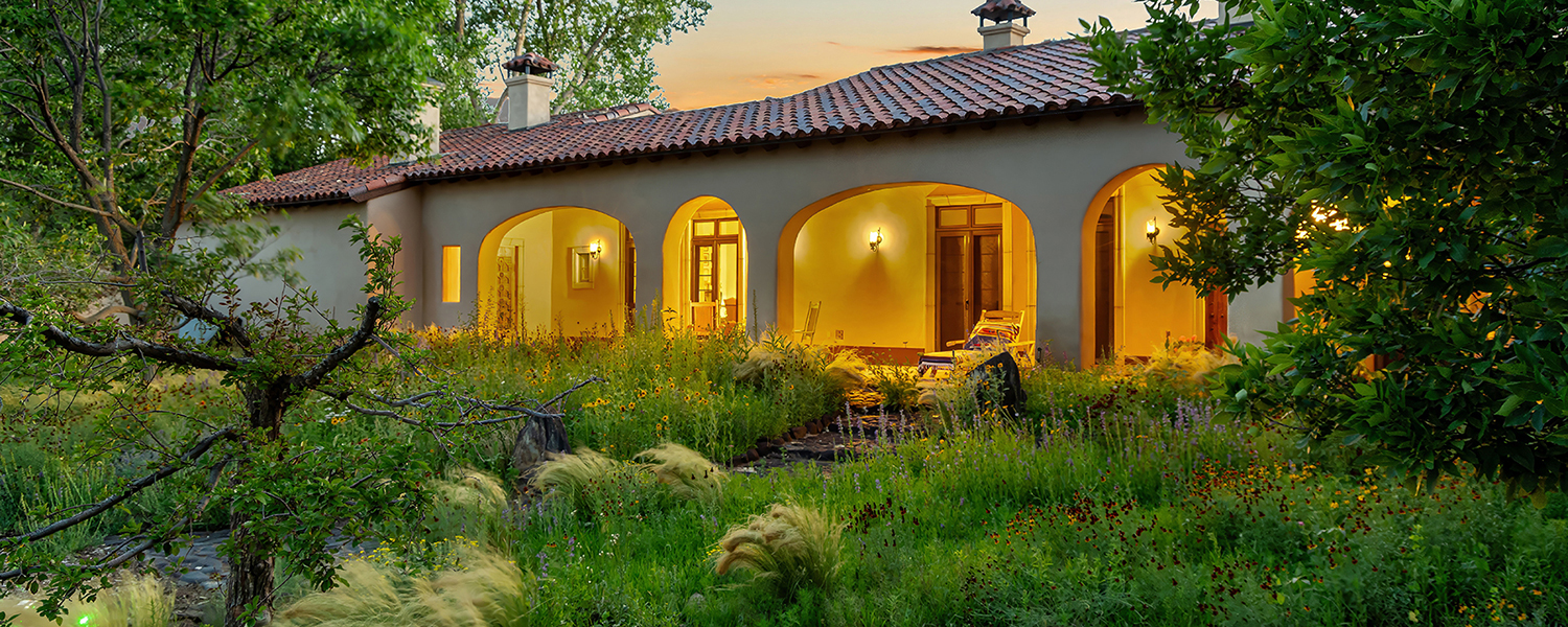 Lit portico with flowers and lush green front garden